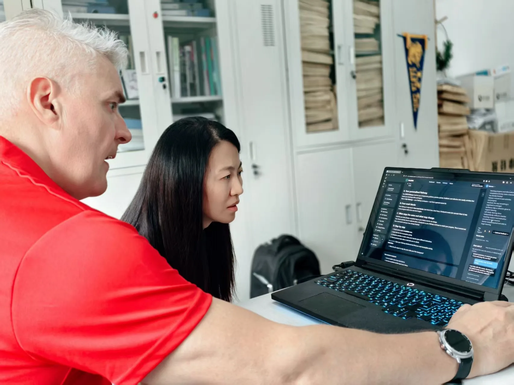 Two participants reviewing the EduZMS learning platform on a laptop / 两位参与者在笔记本电脑上查看 EduZMS 学习平台。