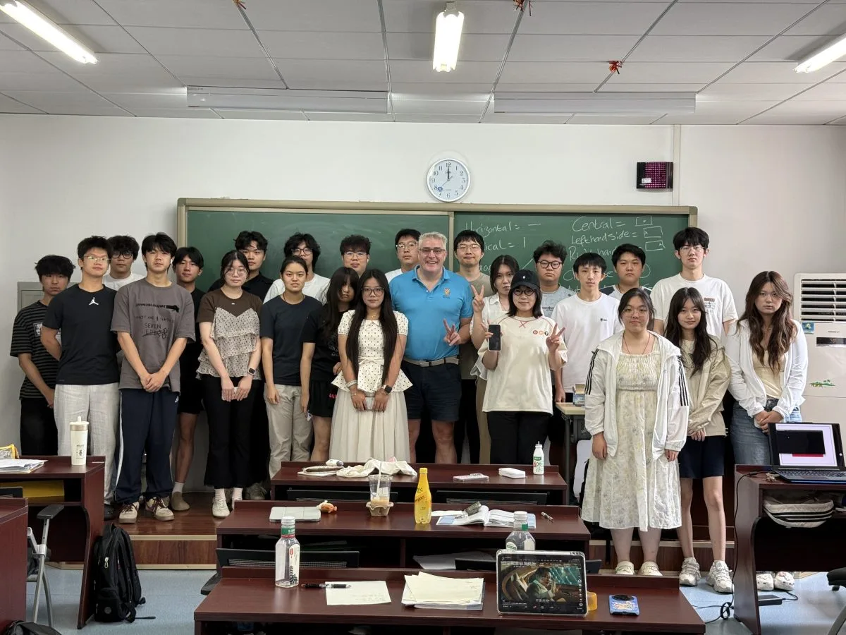 Summer camp participants and James Foster posing together in a CUEB classroom.