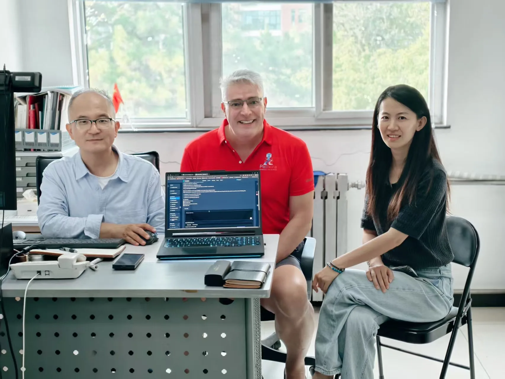 Three participants gathered around a laptop during BUA staff training / 北京农学院教职员工培训中,三位参与者围坐在笔记本电脑旁。